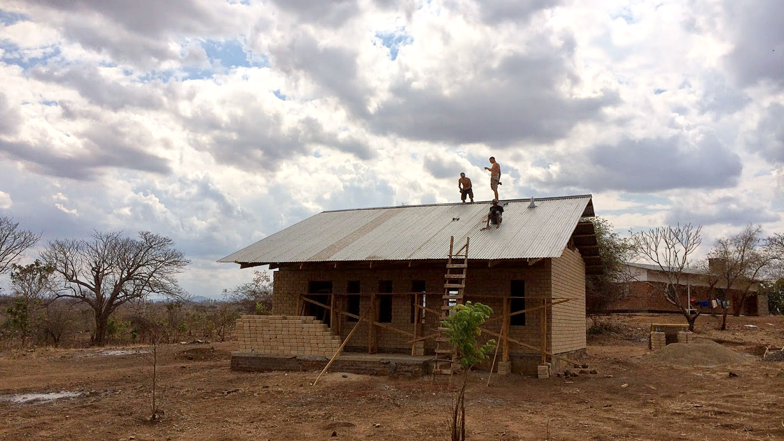 Adding the metal sheet roof cladding to the school building.